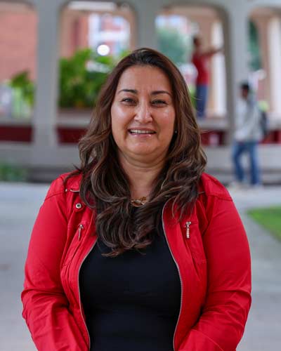 Dr. Berna Tokgoz, outside image of smiling woman with long brown hair wearing black shirt with red jacket